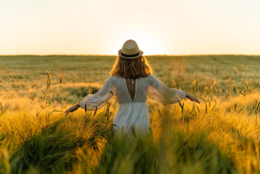 devojka u polju rasirenih ruku u zalasku sunce